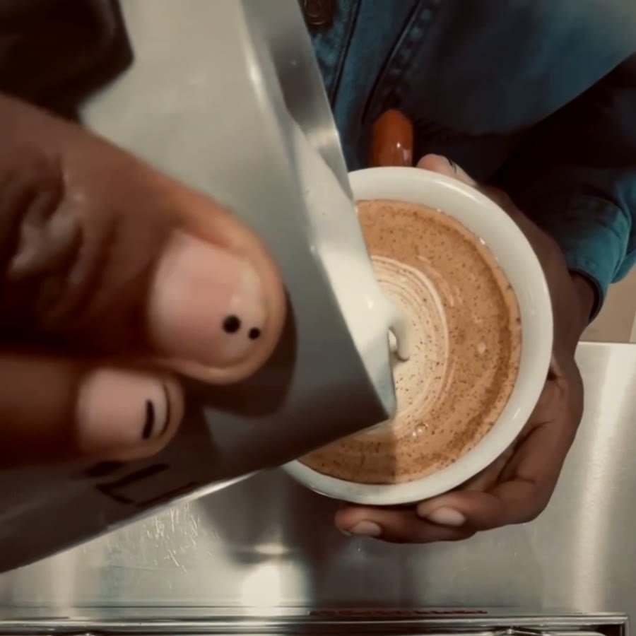 A Tèta barista carefully pouring milk to create latte art